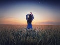 Girl in the golden wheat field at sunset. Beautiful twilight scenery under the summer starry sky with crescent moon. Magical