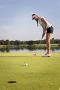 Girl golfer putting ball on green. Royalty Free Stock Photo