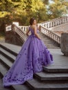 Girl in gorgeous purple long dress standing on the stairs Royalty Free Stock Photo