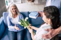 The girl and grandfather giving flowers and a gift to a grandmother. Royalty Free Stock Photo