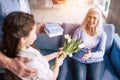 The girl and grandfather giving flowers and a gift to a grandmother. Royalty Free Stock Photo