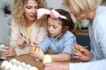 Girl with grandma and mother decorating Easter eggs together