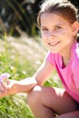 Girl, grass and portrait of kid with flower in nature for spring enjoyment, vacation and development. Happy, child and Royalty Free Stock Photo