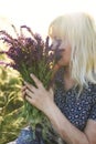 The girl among the grass steppe feather grass with a bouquet of flowers of sage. The atmosphere of outdoor recreation among flower