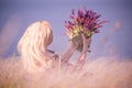 The girl among the grass steppe feather grass with a bouquet of flowers of sage. The atmosphere of outdoor recreation among flower