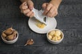 A girl grates garlic on a grater on a wooden table