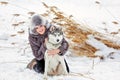 The girl in the gray coat smiling next to a grey husky dog in wi