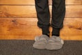 Girl in gray slippers and gray pants stands on the floor of the house on a dark carpet