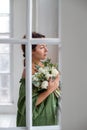 Vertical portrait of a brunette by the window with a bouquet of hyacinths