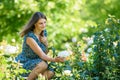 Girl in green garden admires white rose on bush