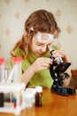 Girl attentively looks into microscope