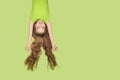 Girl in green T-shirt hanging upside down with flying hair. Copy space