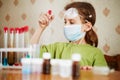 Girl in respirator attentively looks at test tube Royalty Free Stock Photo