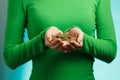 Girl in green turtleneck holding gold coins in hands