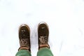 A girl in green pants walks through the snow in winter.