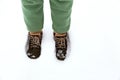 A girl in green pants walks through the snow in winter.