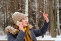 Girl greets someone by hand, talking on the phone in the winter in the open air Royalty Free Stock Photo