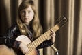 Girl with a guitar on a brown background. Child with a musical instrument