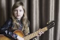 Girl with a guitar on a brown background. Child with a musical instrument