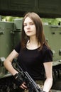 Girl with a gun, posing near the armored vehicle