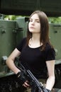 Girl with a gun standing near the armored cars