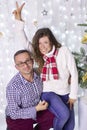 A girl and a guy in Christmas clothes pose for the camera, laugh against the backdrop of illumination next to a decorated