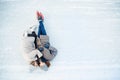 Girl and guy cuddle on snow in skates ice rink in winter, top view. Couple lover holidays