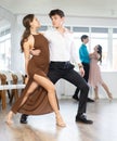 Girl and guy in festive clothes dancing slow ballroom dance during group lesson in choreography studio Royalty Free Stock Photo