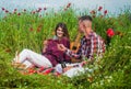 girl and guy in field. romantic couple drink wine in poppy flowers on date. family summer vacation. happy man and woman Royalty Free Stock Photo