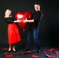 A girl and a guy hold a heart balloon inflatable, a flirting board, on the floor hearts are lovely . shape. event