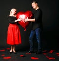 A girl and a guy hold a heart balloon inflatable valentine, happiness flirt, on the floor hearts are a beautiful layout