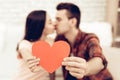 A Girl And A Guy Kiss Holding Red Heart Origami.