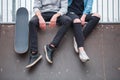 A girl with a guy is sitting on the run-up next to a skateboard in a skate park. Front view Royalty Free Stock Photo