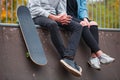 A girl with a guy sitting on the run-up next to a skateboard in a skate park Royalty Free Stock Photo