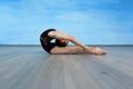 A girl gymnast in a black gymnastic swimsuit doing gymnastic exercise deflection back on the floor on a blue background Royalty Free Stock Photo