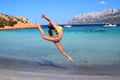 Girl Gymnast, jump, Sardinia, Porto Istana beach facing the island of Tavolara. Royalty Free Stock Photo