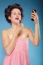 Girl in hair curlers applying red lipstick Royalty Free Stock Photo