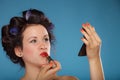 Girl in hair curlers applying red lipstick Royalty Free Stock Photo