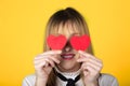 Girl with half smile with two small red hearts in hands closing eyes on yellow background. Valentine`s Day Royalty Free Stock Photo