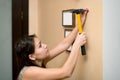 Girl hammer a nail into the wall to hang a photo frame