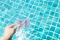 Girl hand dipping water testing test kit in clear swimming pool water to test pH and chlorine