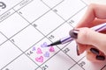 Girl hand drawing and coloring heart shape in calendar for Valentines day with felt pen Royalty Free Stock Photo