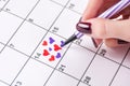 Girl hand drawing hearts in calendar with felt pen for Valentines day Royalty Free Stock Photo