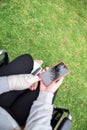 Girl with a hand and a foot bandaged in a wheelchair. Mobile phone screen in black on green grass