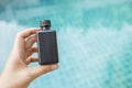 Girl hand holding black plastic bottle over blurred blue swimming pool water background Royalty Free Stock Photo