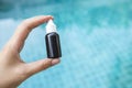 Girl hand holding black plastic container over blurred blue swimming pool Royalty Free Stock Photo