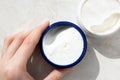 Girl hand holding face cream, close-up. Moisturizer in container on marble background, top view Royalty Free Stock Photo