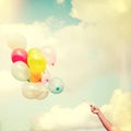 Girl hand holding multicolored balloons done with a retro vintage Royalty Free Stock Photo