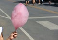 Girl hand holding a pink cotton candy stick with copy space blurred road background Royalty Free Stock Photo