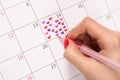 Girl hand with pencil drawing heart shape in calendar for Valentines day Royalty Free Stock Photo